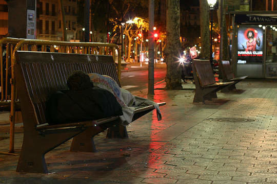Hombre durmiendo en un banco en Barcelona. Fotografía Asociación Arrels.
